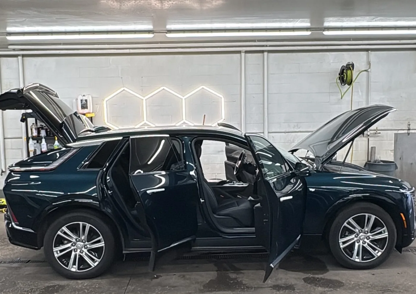 Full detail complete — dark navy Cadillac SUV with doors and hood open in the detail bay — Dublin, Ohio | Touch It Up Automotive